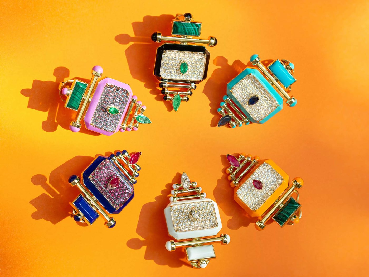 Six enamel and pavé Capture rings arranged on a saffron ground, each crowned with a marquise emerald, sapphire or ruby.