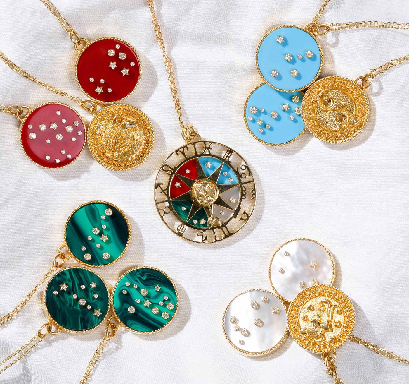 Cosmic Love constellation medallions in carnelian, turquoise, malachite and mother-of-pearl, set with diamond stars, scattered on white silk.